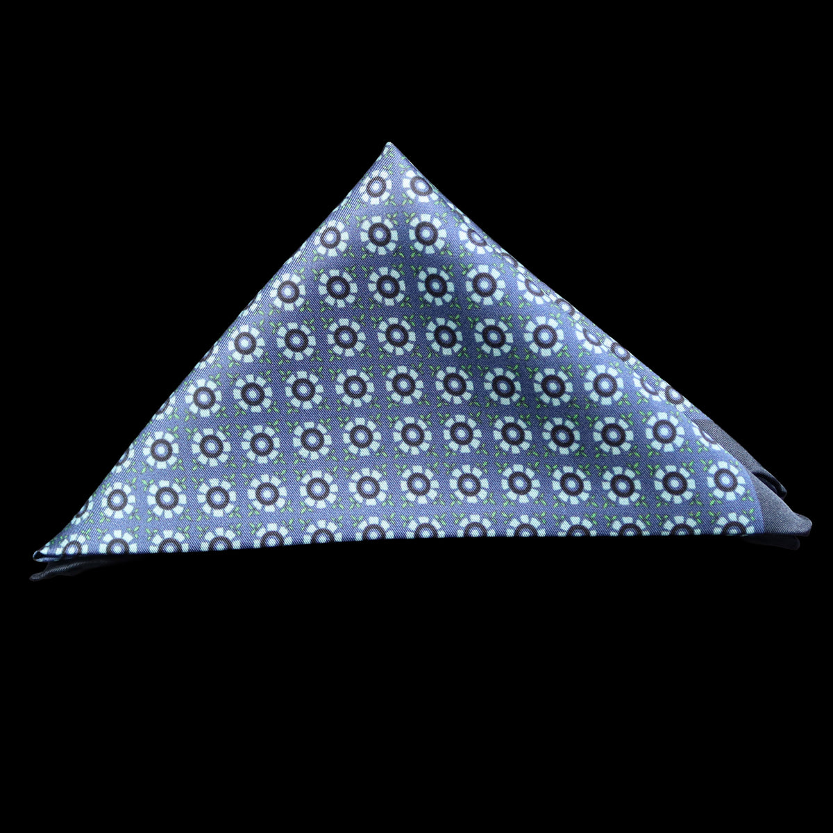 A blue pocket square with a repeating floral pattern in light blue, folded into a triangle and set against a solid black background.