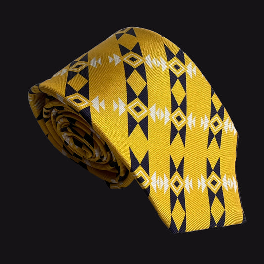 A rolled yellow Rumi London silk necktie with a geometric pattern of black diamonds and white arrow motifs, set against a solid black background.