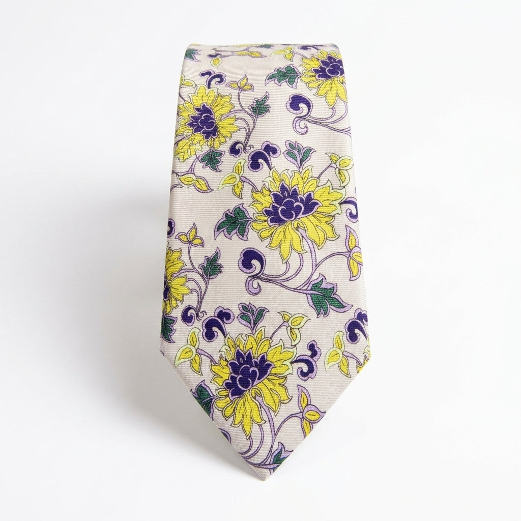 A silk necktie with a yellow and purple floral pattern on a cream background, displayed against a plain white background.