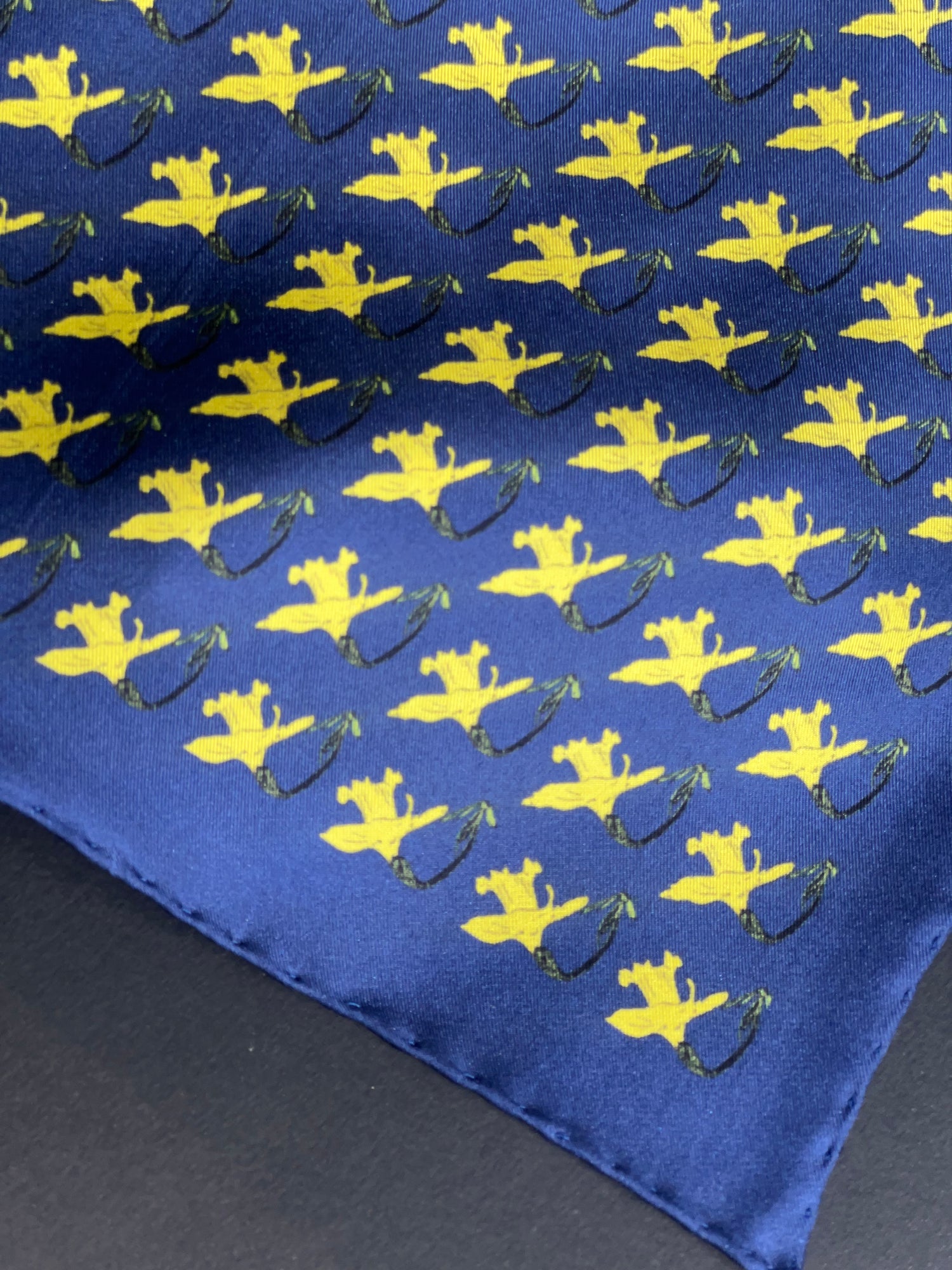 A close-up of a blue pocket square featuring a repeating pattern of daffodils with green stems.