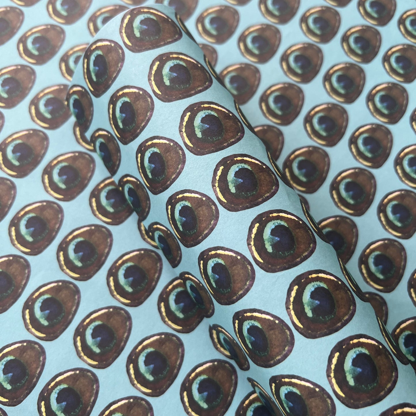 Rumi London eco-friendly wrapping paper in repeat peacock feather print on a blue base