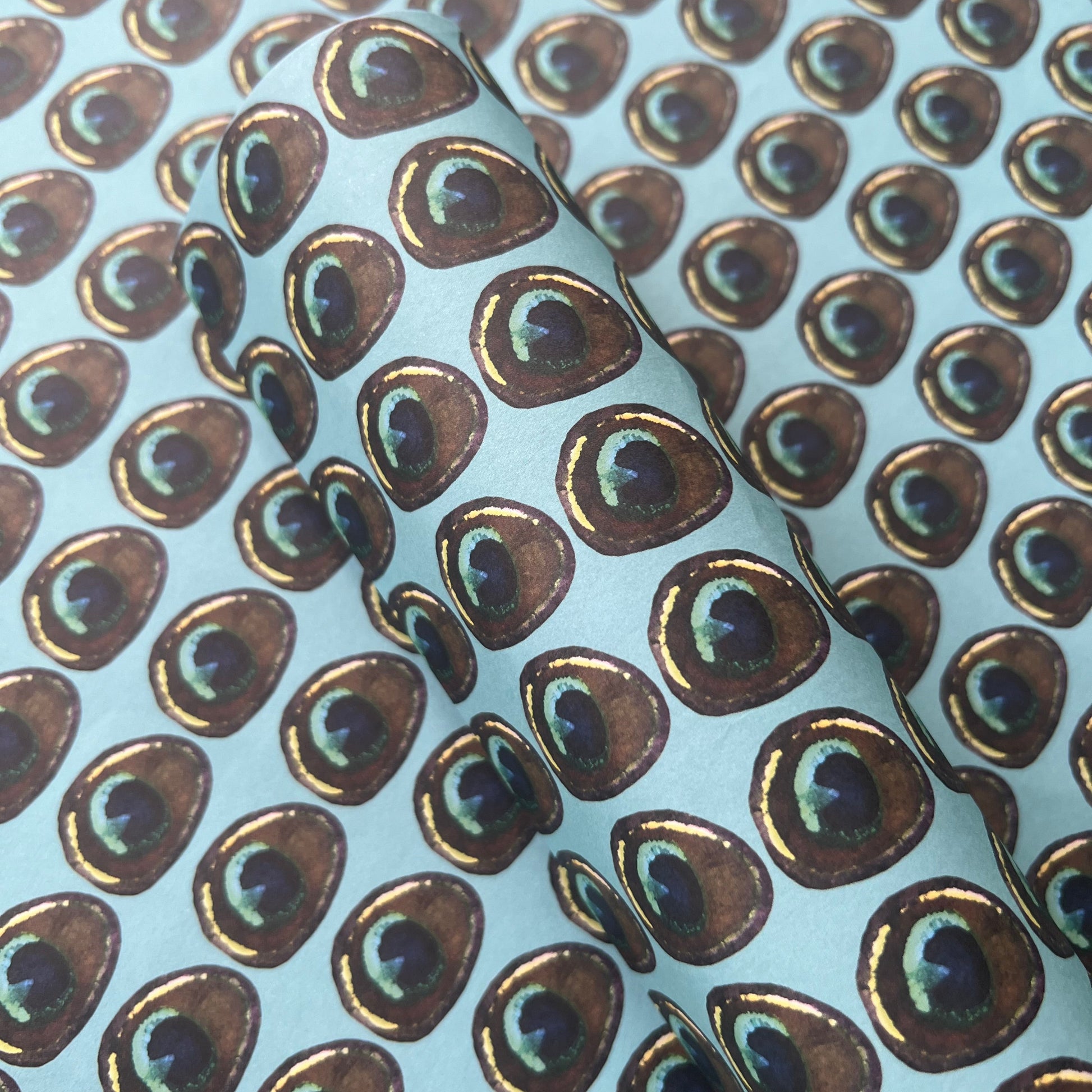Rumi London eco-friendly wrapping paper in repeat peacock feather print on a blue base