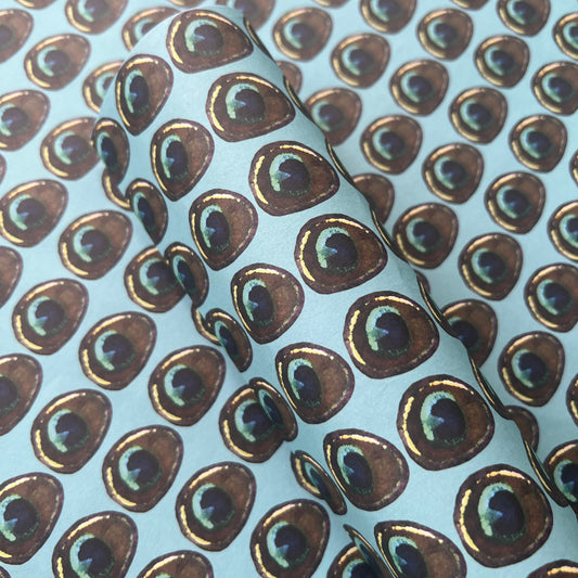 Rumi London eco-friendly wrapping paper in repeat peacock feather print on a blue base
