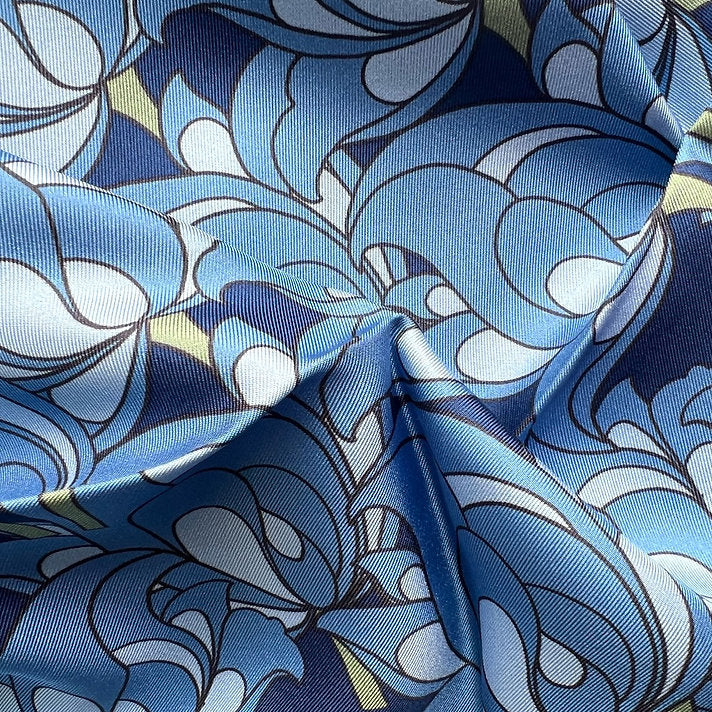 Close-up of square silk scarf with blue florals on a blue background.