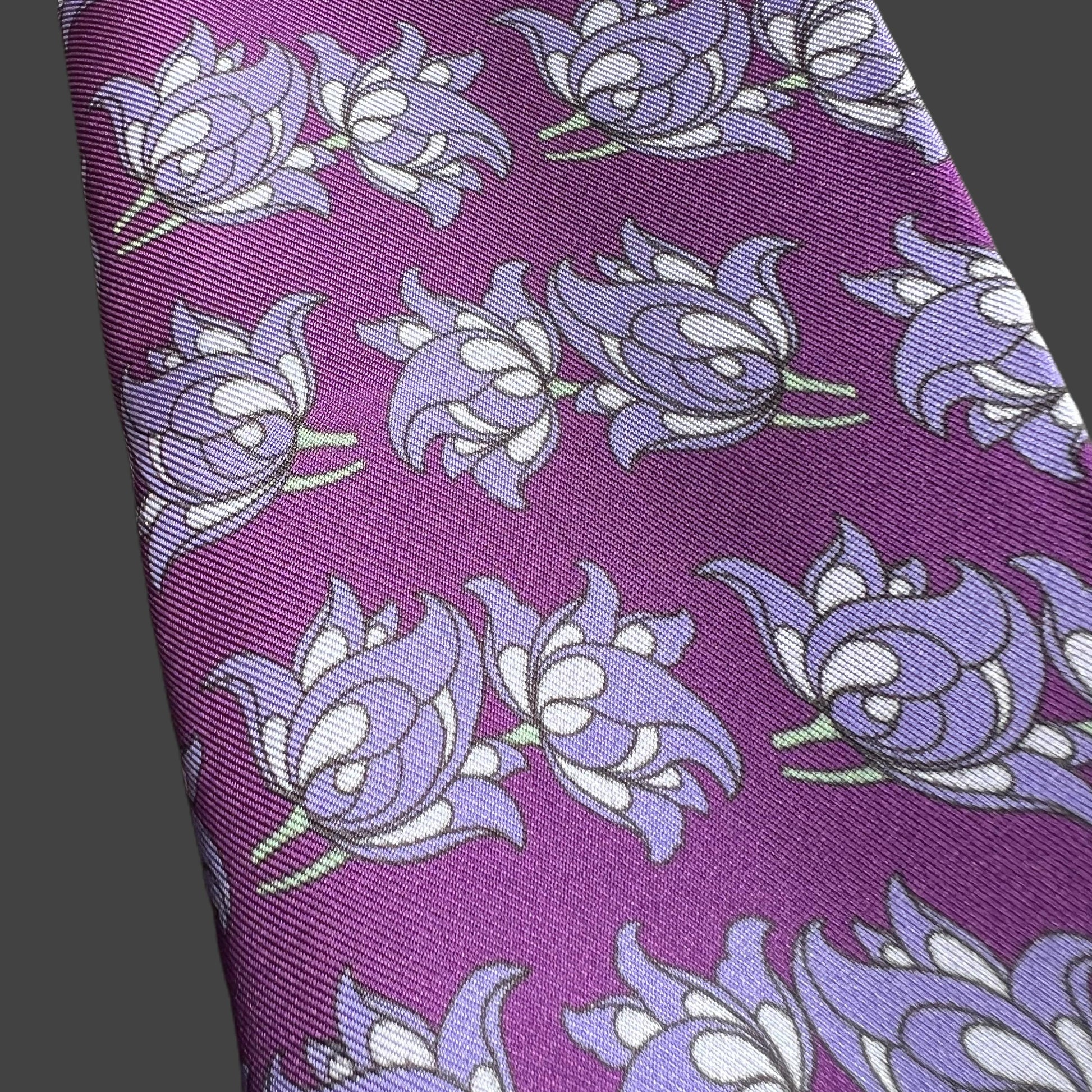 Folded purple floral silk twill silk scarf with floral motif repeat pattern on a purple base.