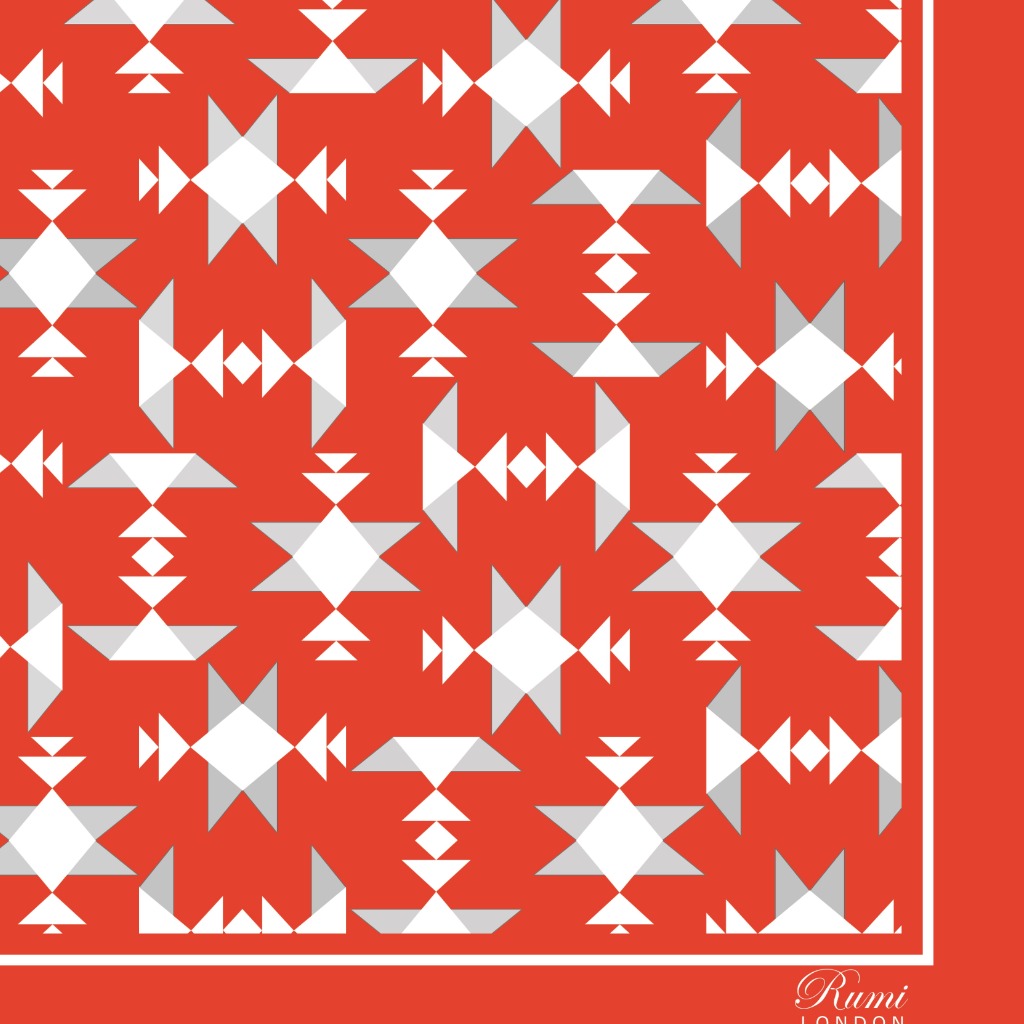 Close-up of square silk scarf with white geometric pattern on an orange background and border.