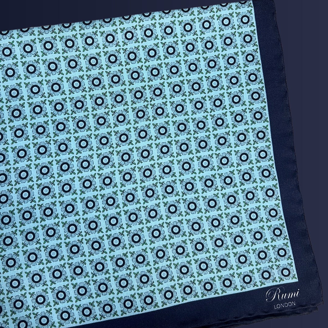 Folded Rumi London floral pocket square with repeat floral motifs on a light turquoise base.