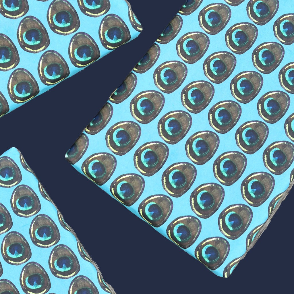 Gifts wrapped in Rumi London eco-friendly wrapping paper in repeat peacock feather print on a blue base.